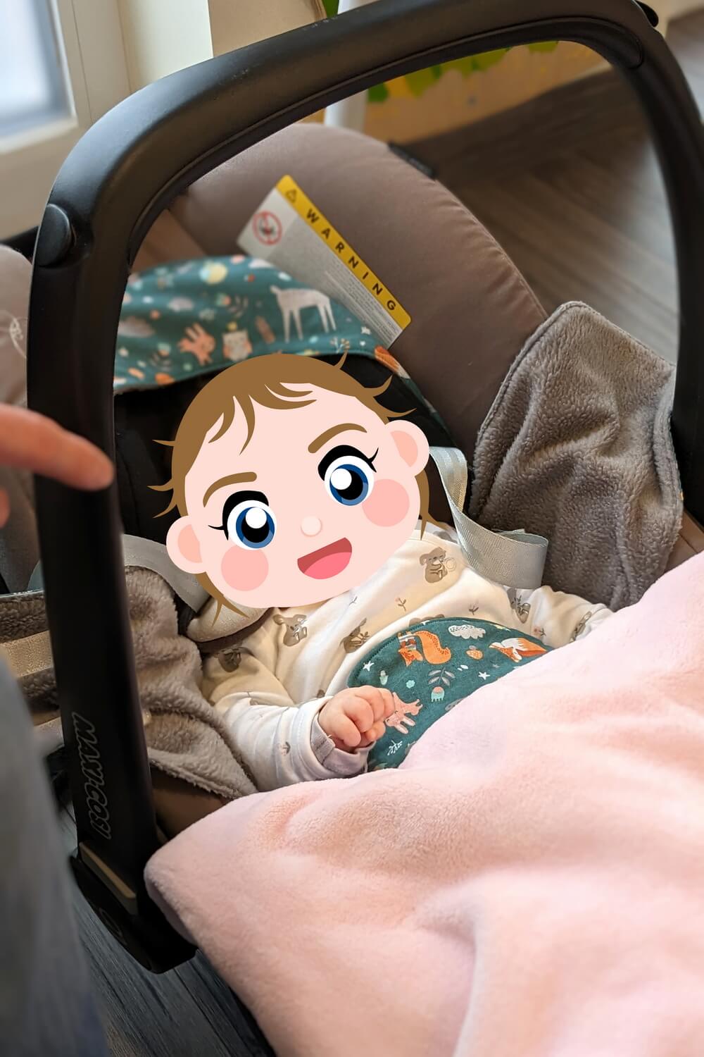 Baby mit Einschlagdecke im Maxi-Cosi