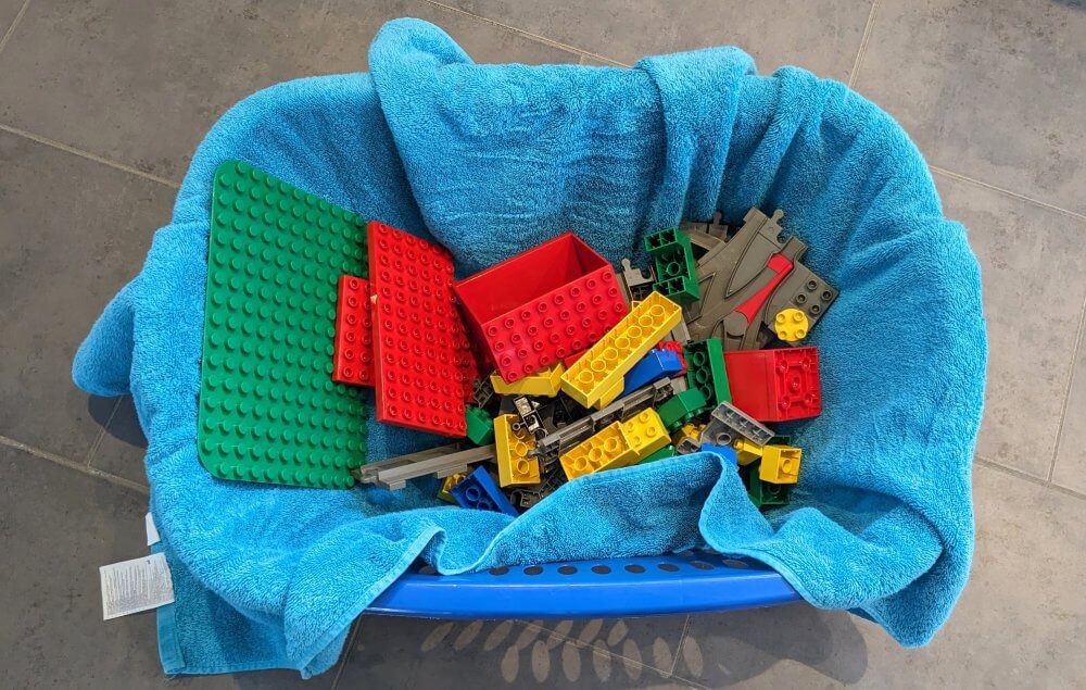 Gewaschene Lego Duplo Steine liegen in einem Wäschekorb auf einem Wandtuch